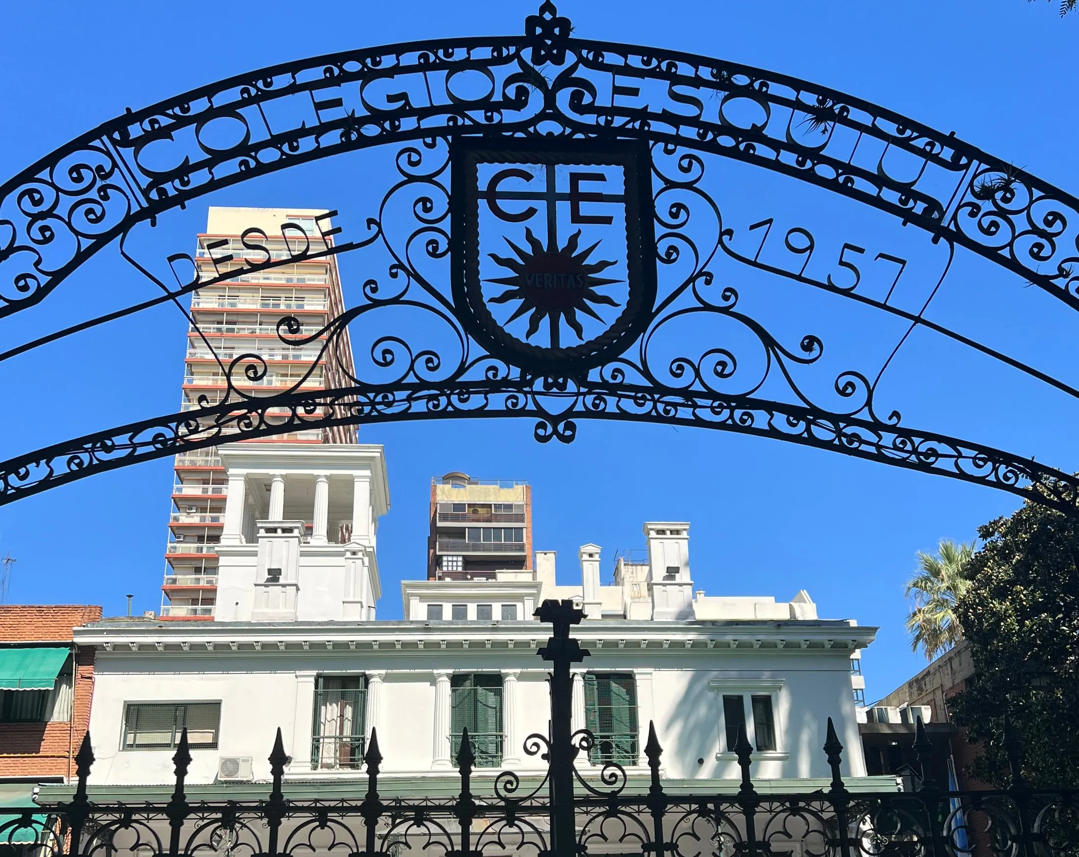 El portón de hierro del colegio, con el escudo Veritas y la casona de fondo