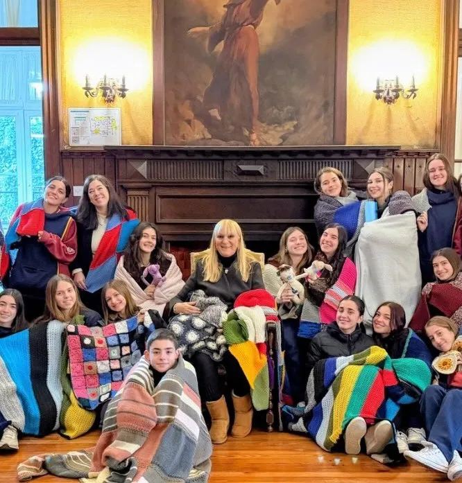 Alumnas del secundario con mantas tejidas frente al hogar de la casona