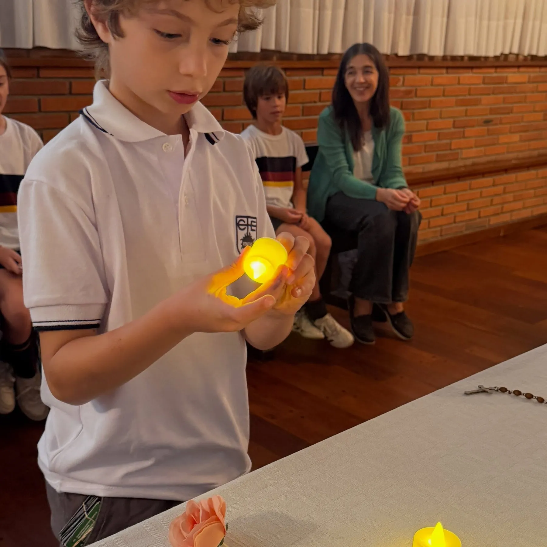 Un alumno sostiene una velita encendida durante una celebración en la capilla